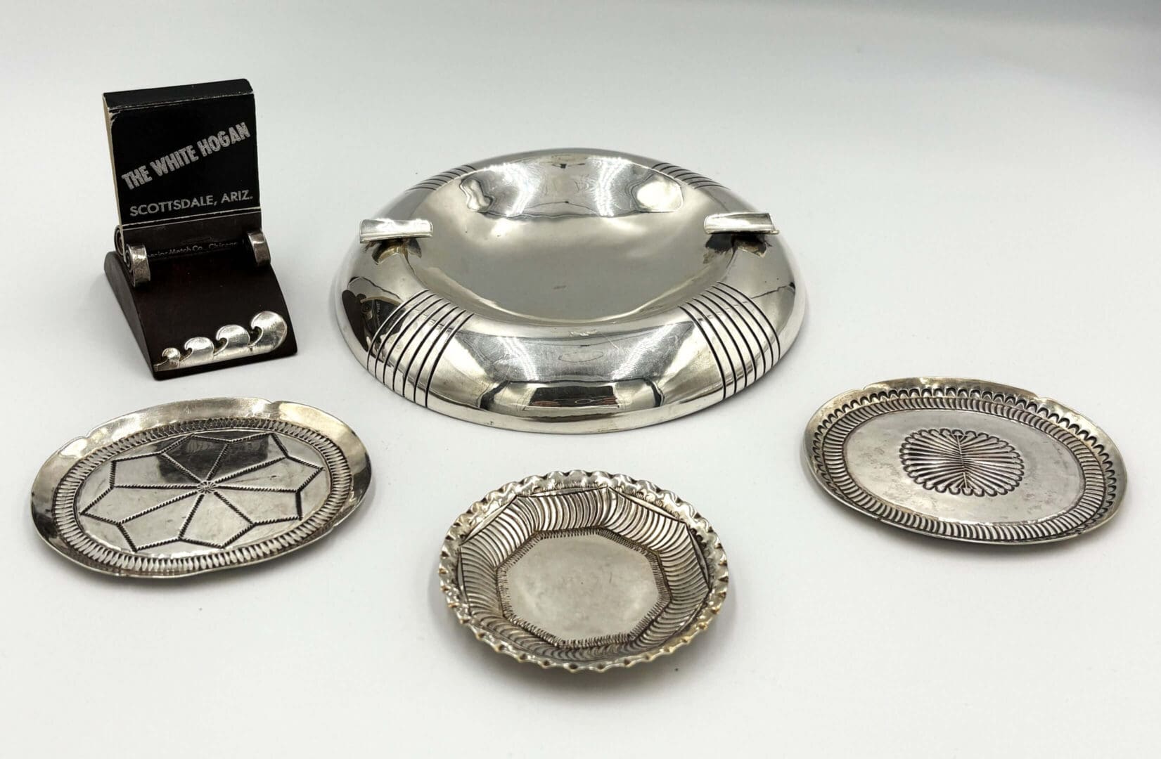 Silver ashtray and coasters on display stand.