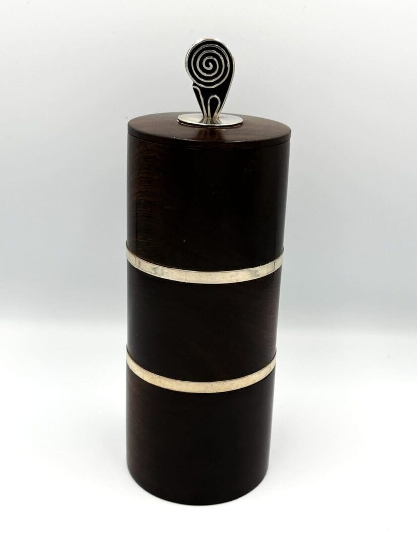 Dark cylindrical container with spiral handle.