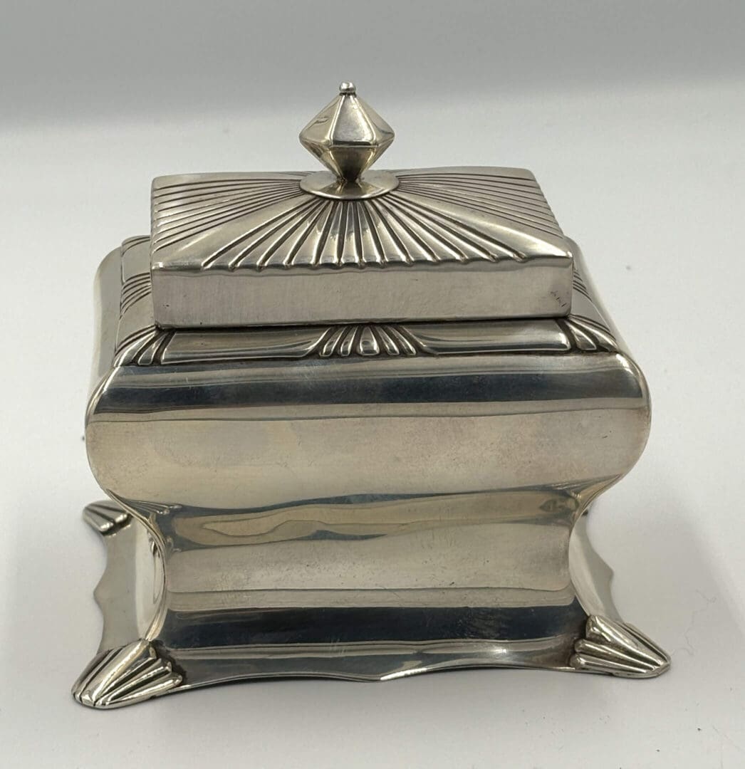Decorative silver box with ornate lid design.
