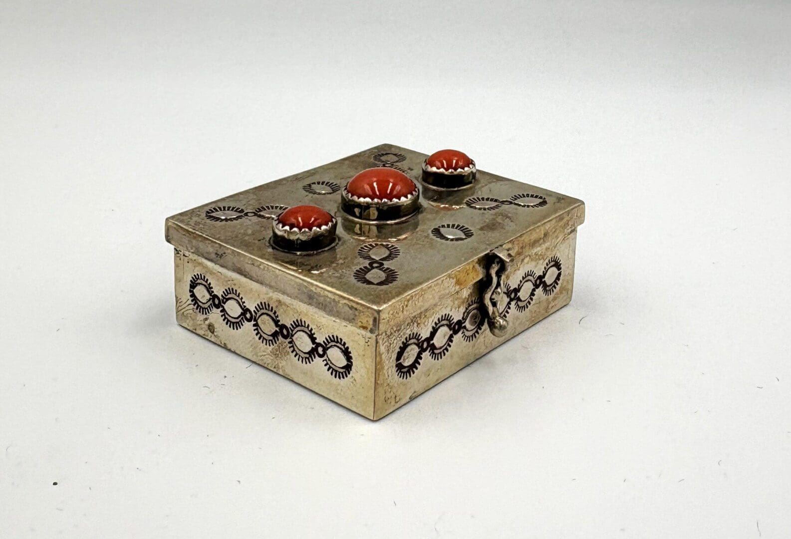 Ornate silver box with red gemstone decorations.