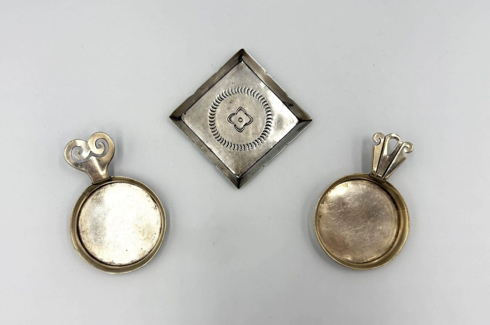 Silver pendants and square plate on display.