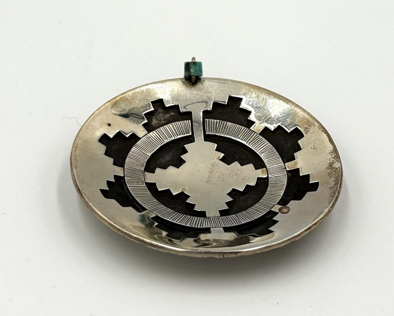 Silver pendant with geometric cutout design.
