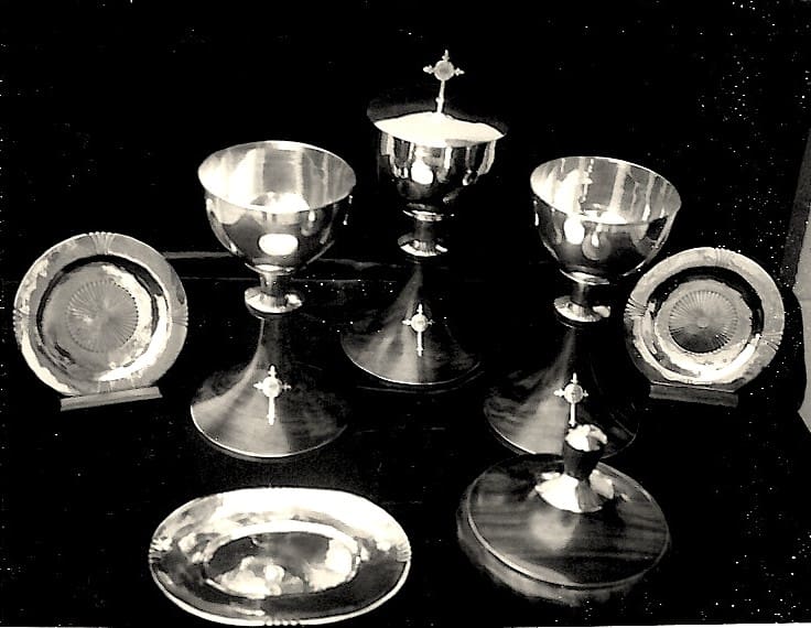 Silver chalices and plates on display.